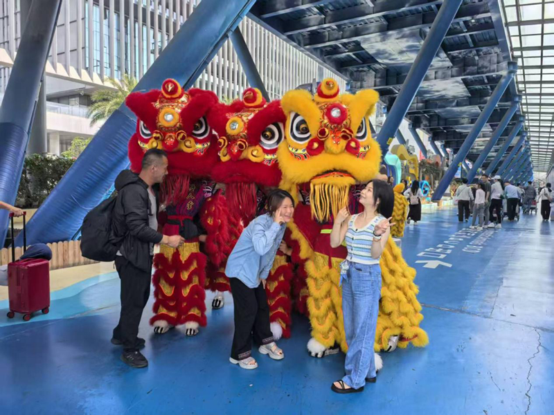在三亚凤凰国际机场，游客与舞狮互动。海南省旅文厅供图